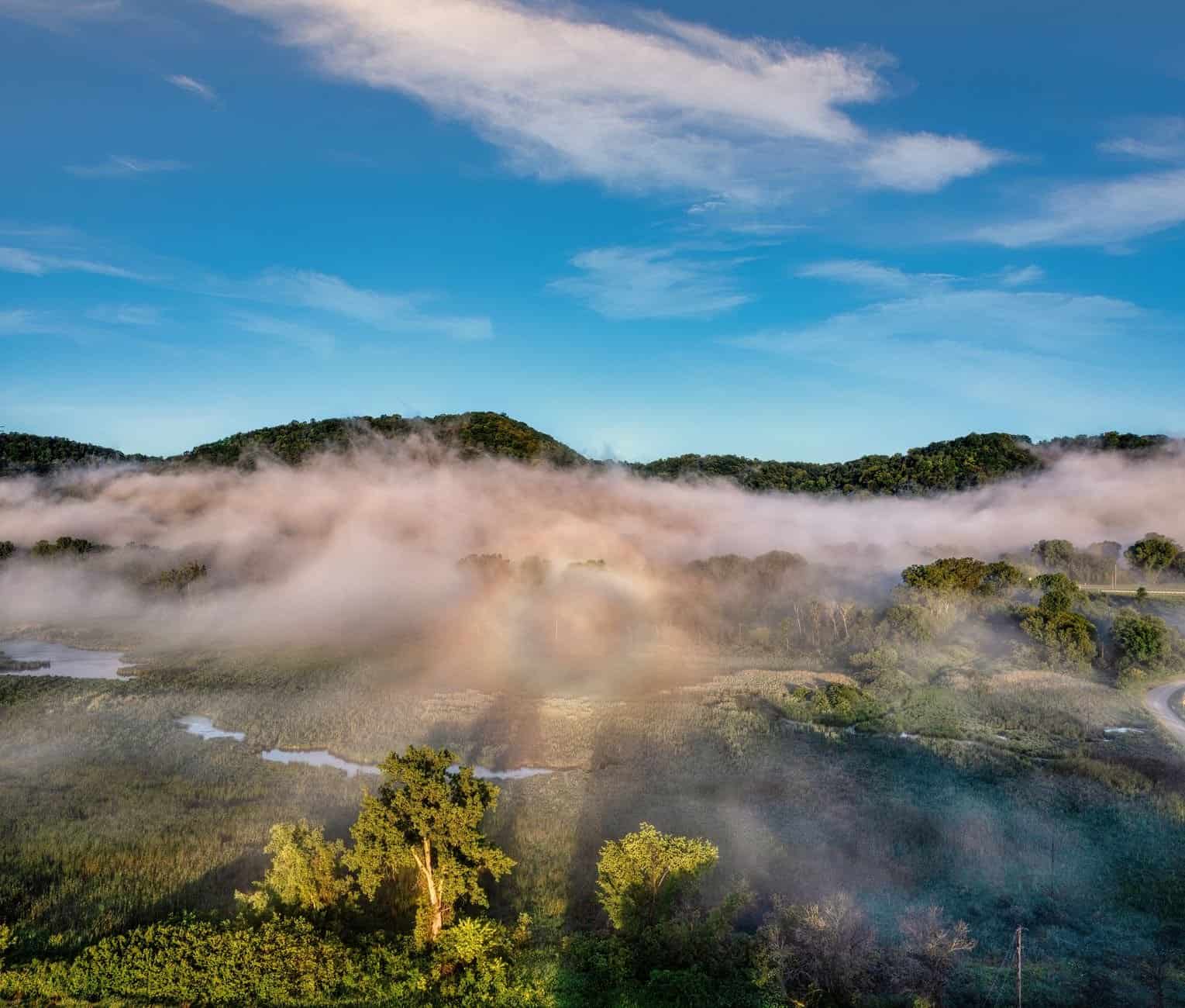 A breathtaking misty morning view in Kellogg, Minnesota, showcasing fog over lush green hills.
