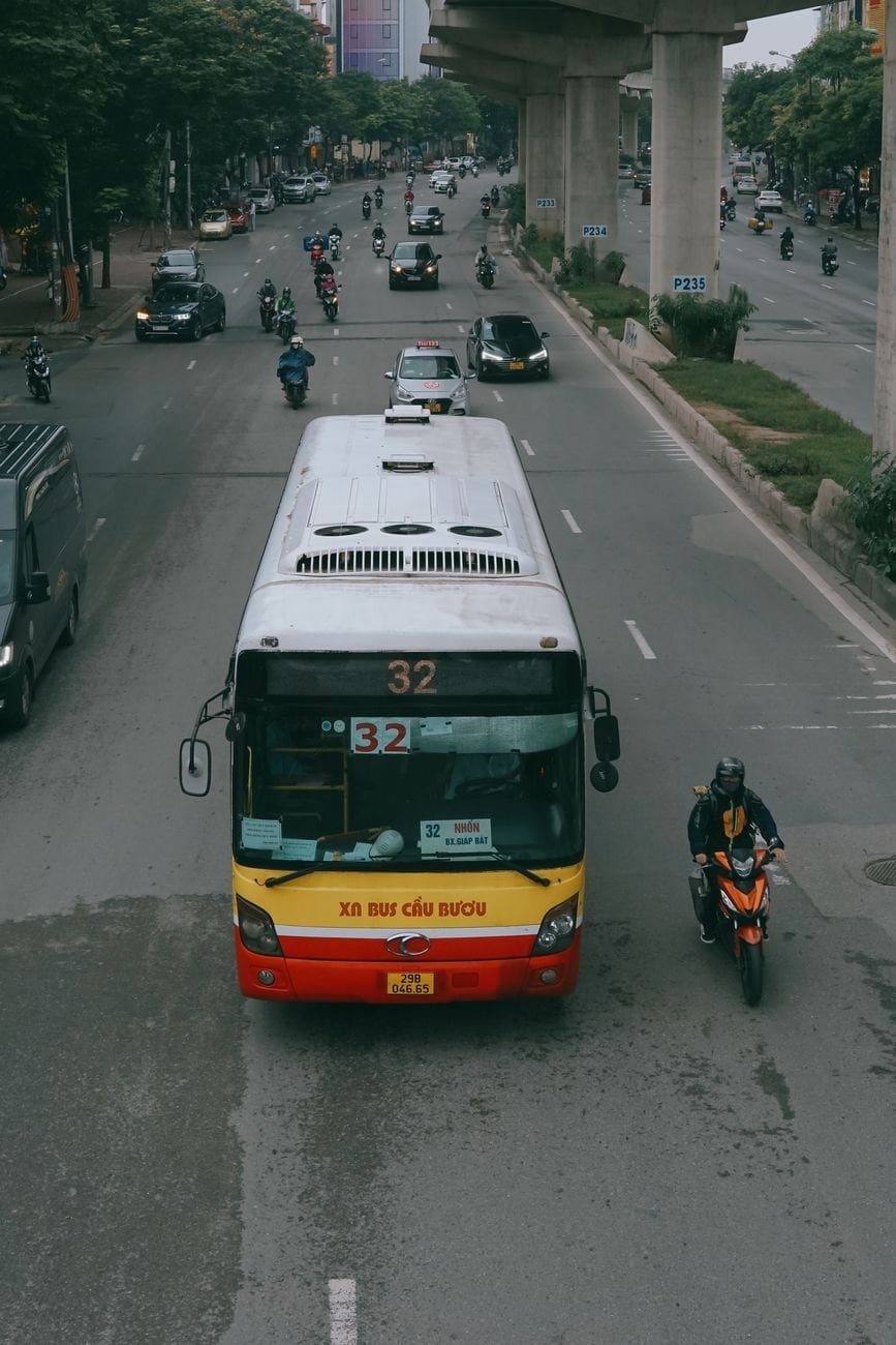 A bustling street in Hà Nội, Vietnam featuring a bus and motorbikes in city traffic.