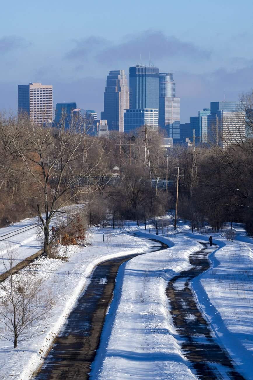 Snow-covered path with a view of the Minneapolis skyline, showcasing urban winter beauty.