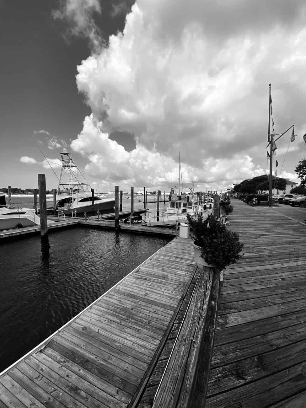 Black and white photo of Beaufort Marina with boats and boardwalk under dramatic clouds.
