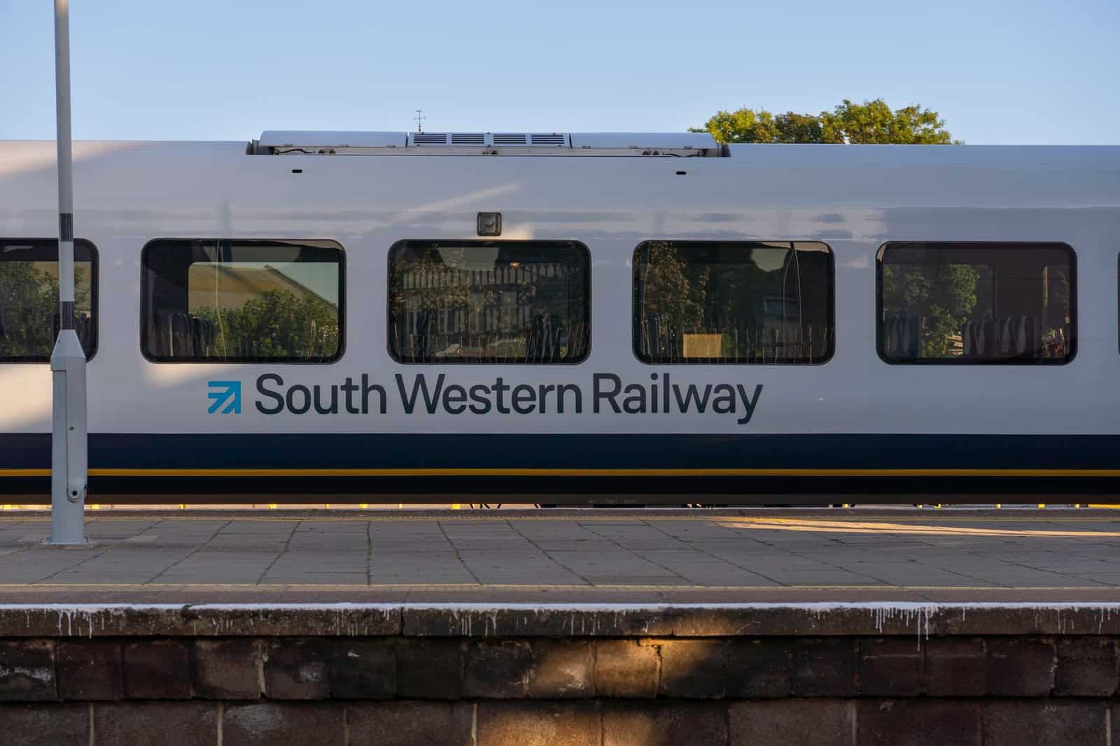 A South Western Railway train at a platform in Portsmouth, UK, during a sunny day.