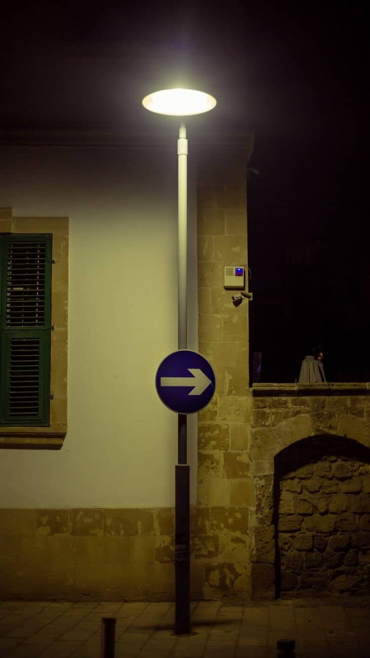 Illuminated street scene featuring a lamp and right arrow sign at night.