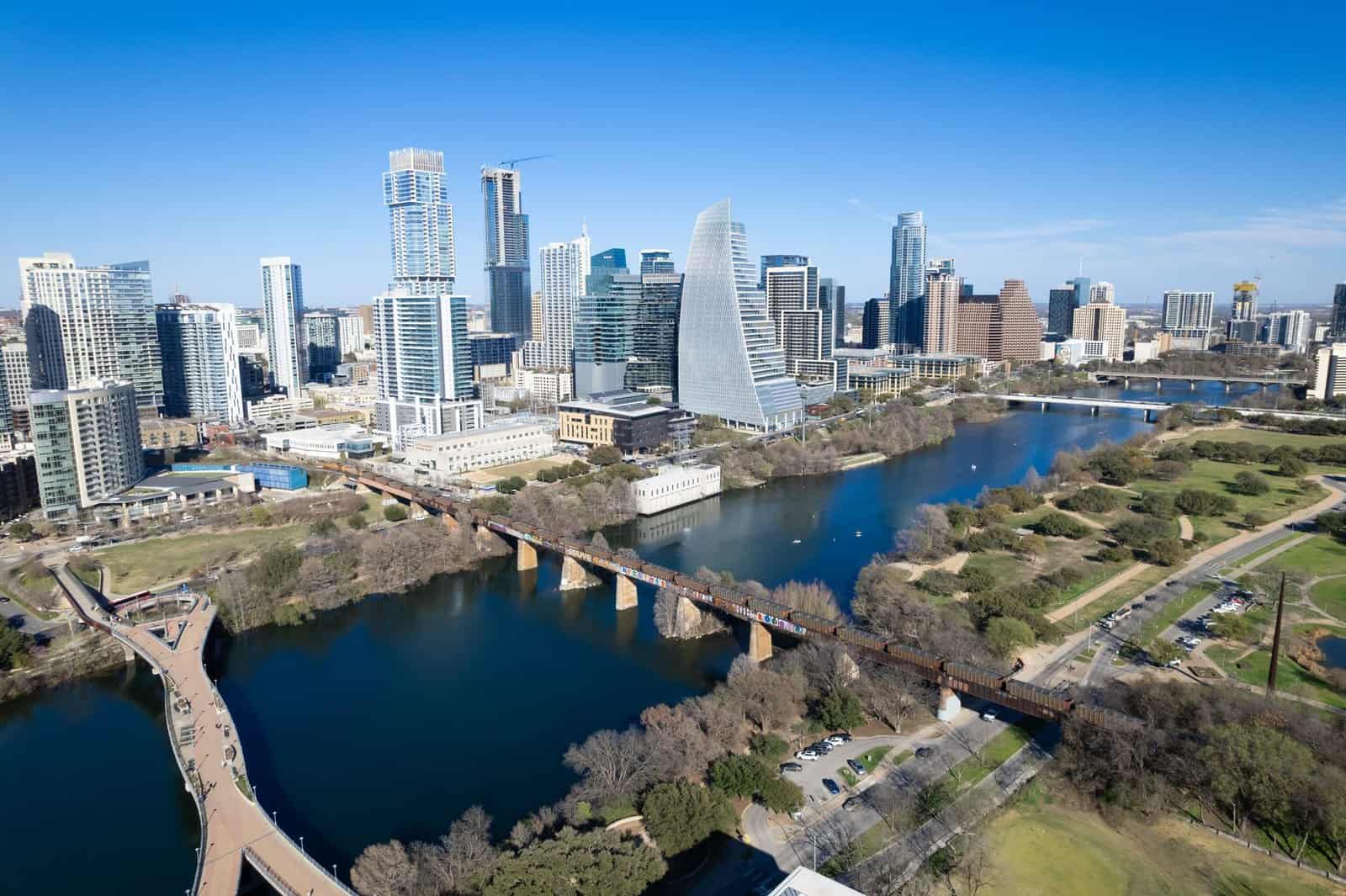Aerial view of Austin, Texas skyline with landmarks including river and footbridge.