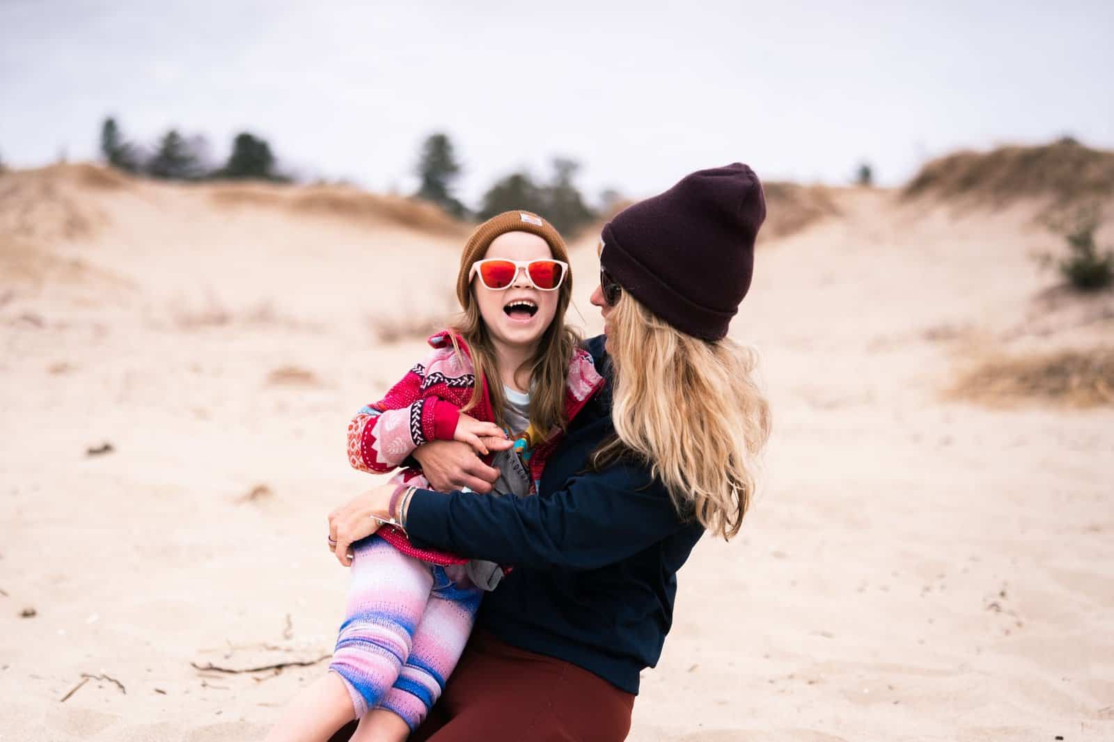 A happy mother and daughter duo enjoying a day at the sandy beach together.