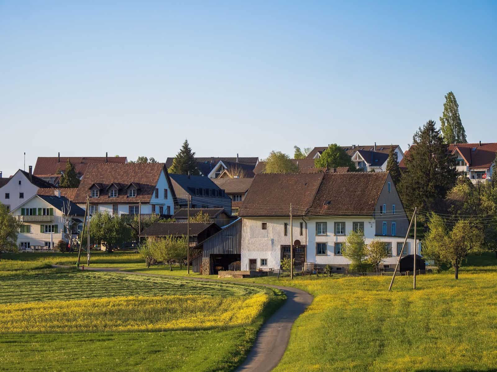Picturesque rural village with traditional houses and green fields under clear blue sky.