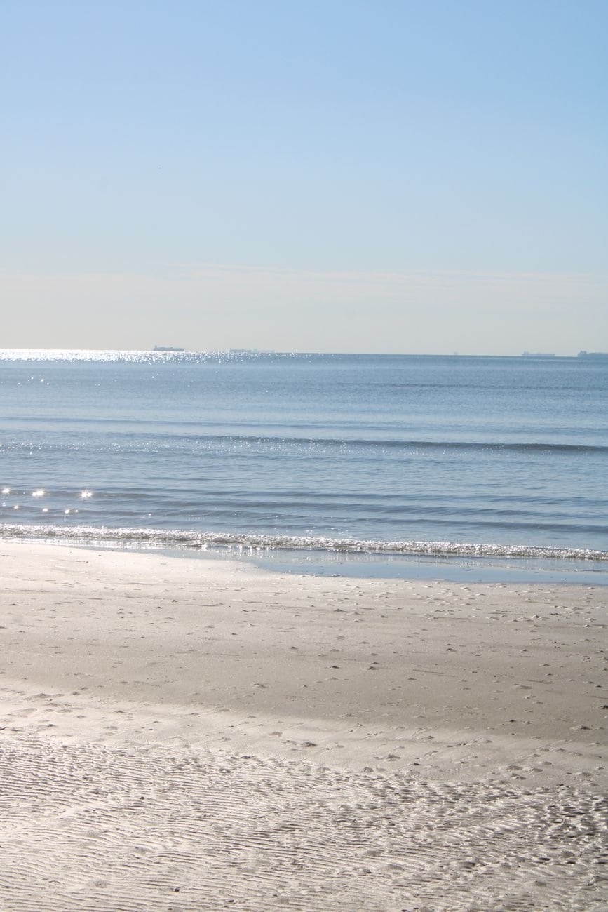 Peaceful beach scene capturing gentle ocean waves and shimmer on a clear day.