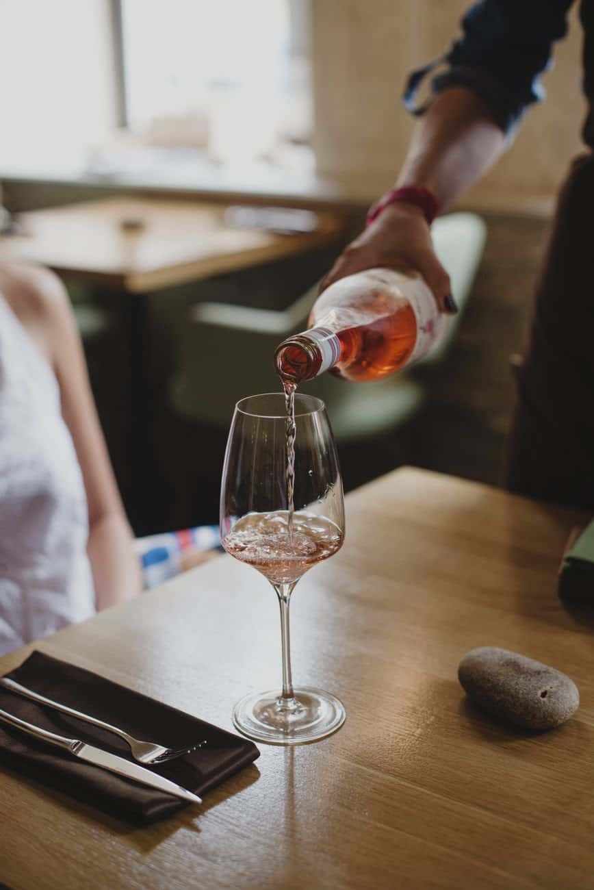 A person pours red wine into a glass, creating a romantic dining atmosphere.