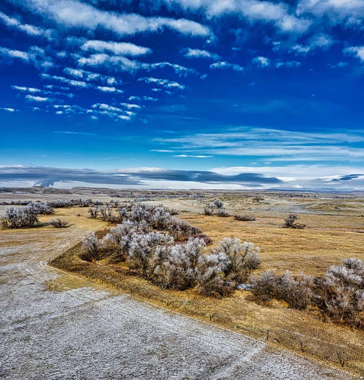 Explore the snow-dusted plains of Douglas, WY, captured from above with clear blue skies.