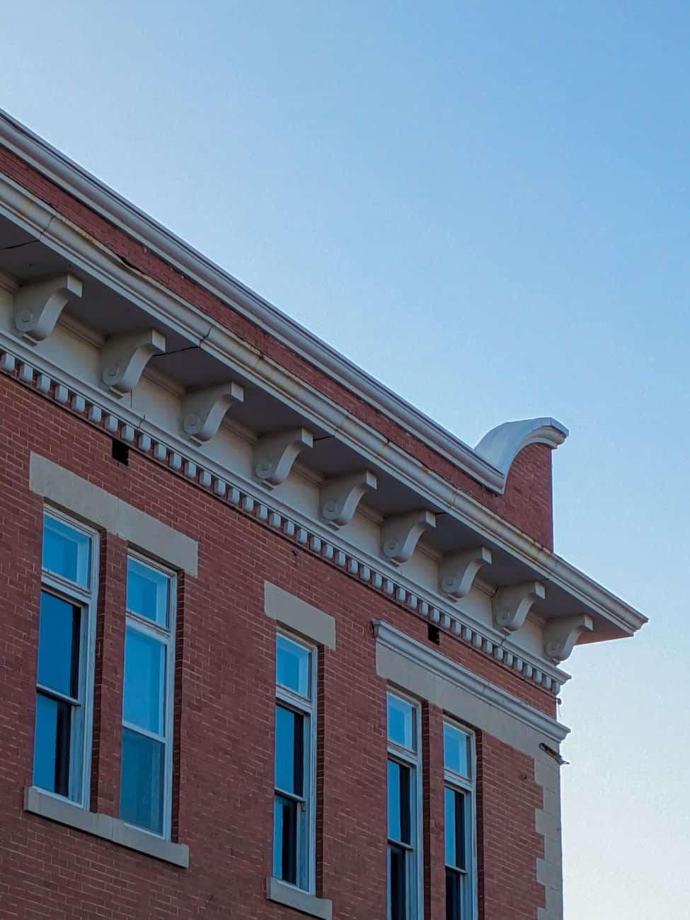 A detailed view of historic brick building architecture with ornate cornices and multiple windows.