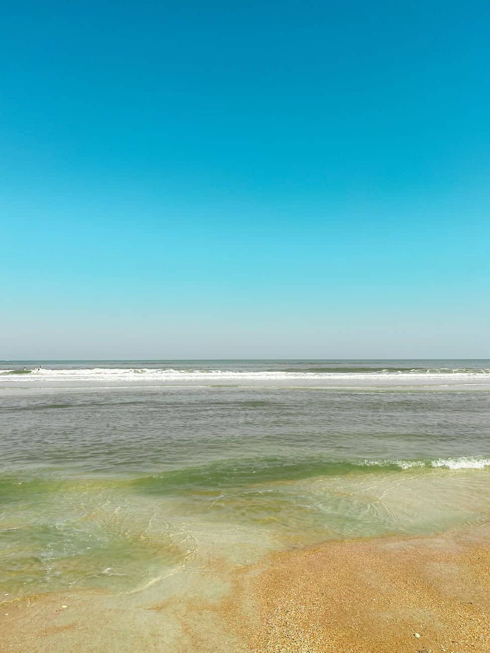 Peaceful view of St. Augustine Beach with clear sky and gentle waves.