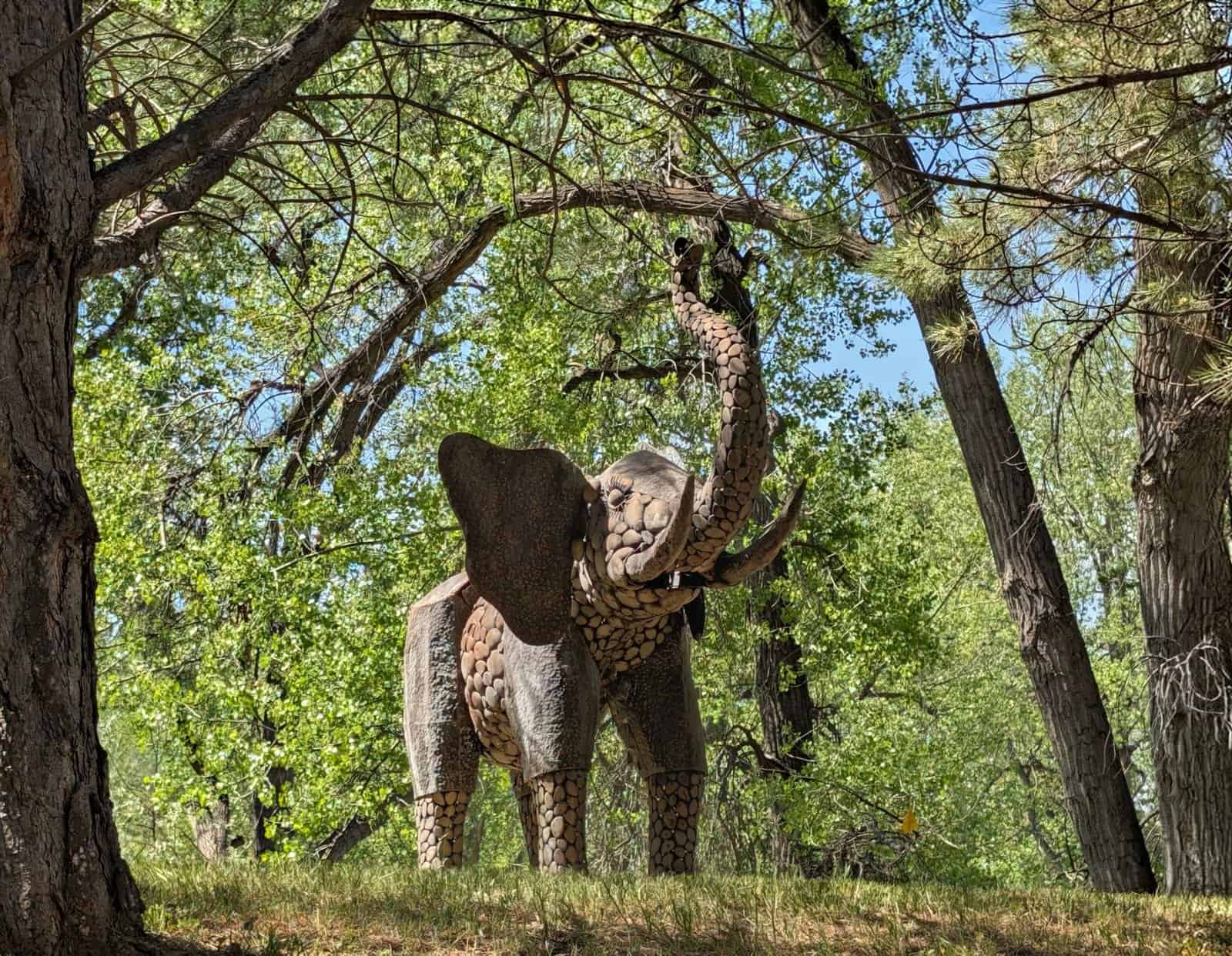 Intricate elephant sculpture surrounded by lush greenery in a Billings park.