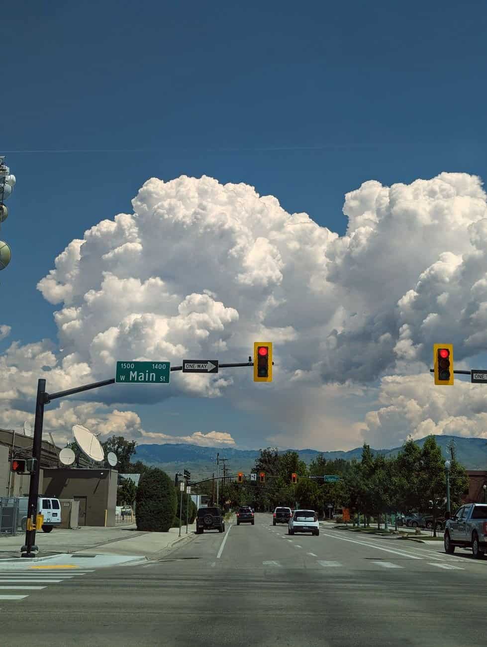 Vibrant summer day in downtown Boise, Idaho, featuring street scene with traffic lights and cumulus clouds.
