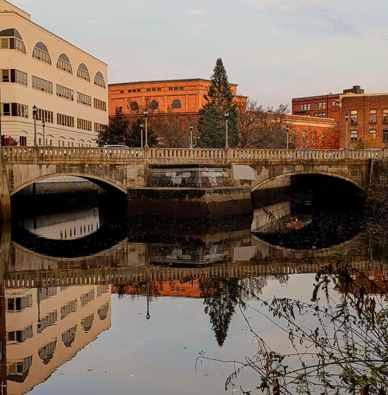 Charming bridge in downtown reflecting in calm water during a serene daytime setting.
