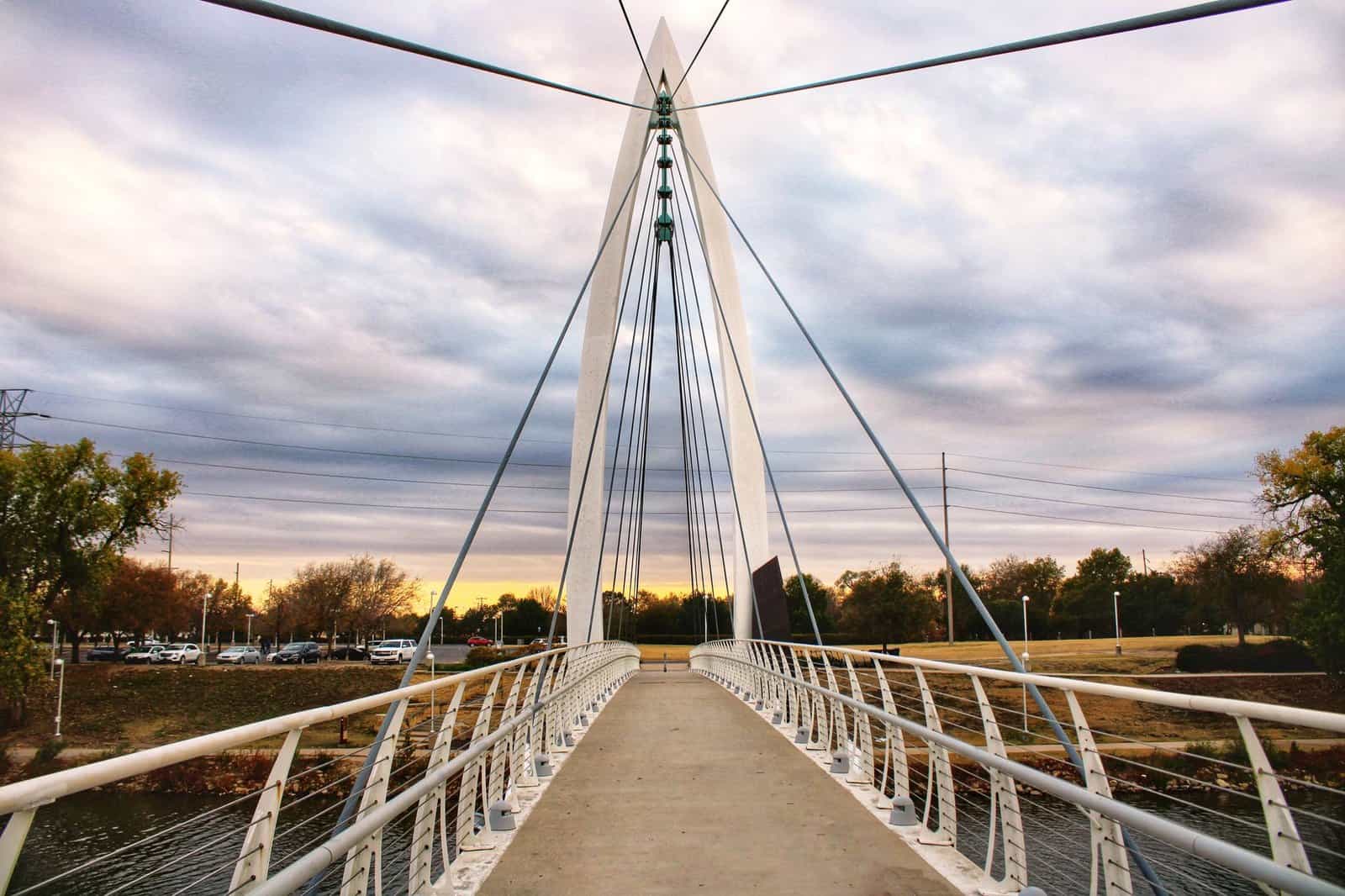 A stunning view of a suspension bridge in Wichita, KS, during sunset, showcasing architectural beauty.