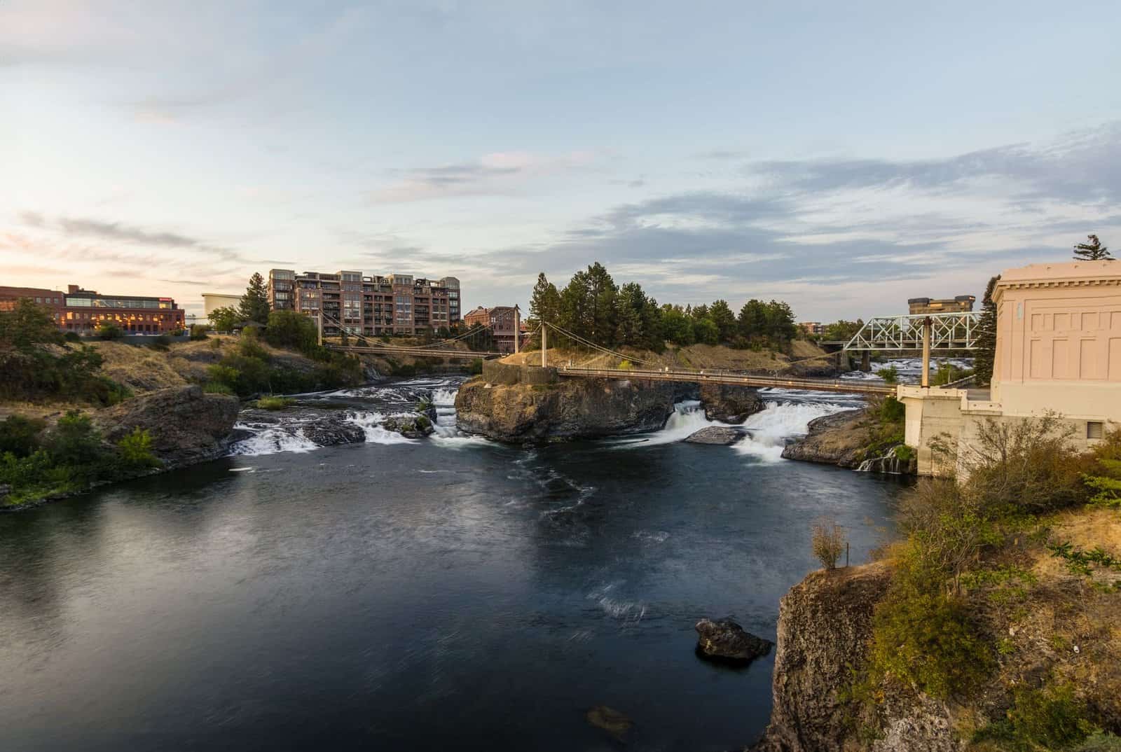 A beautiful view of the Spokane Falls with a bridge and urban landscape, captured at sunset.