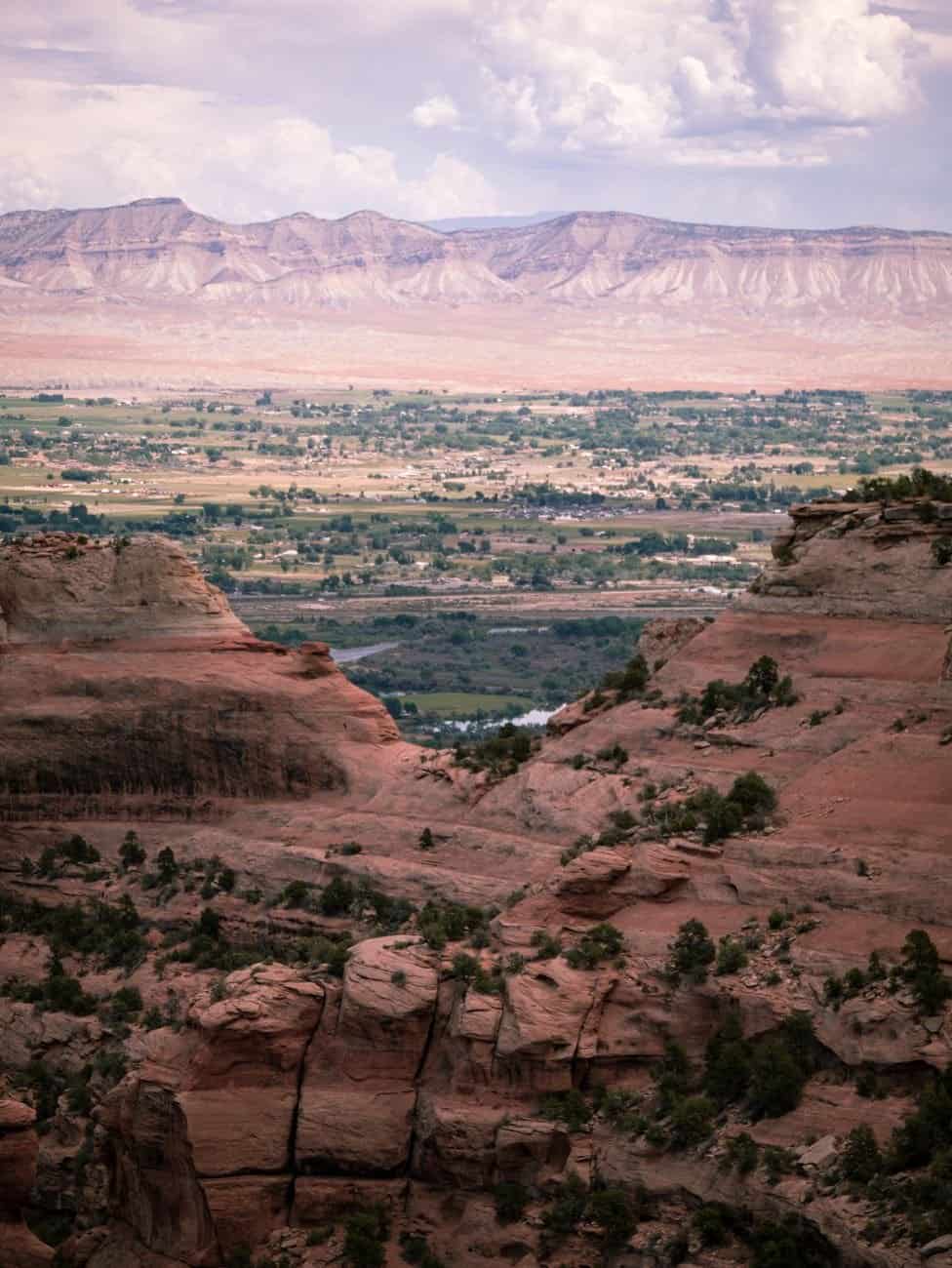 Breathtaking view of a vast canyon with distant flatlands and clouds.