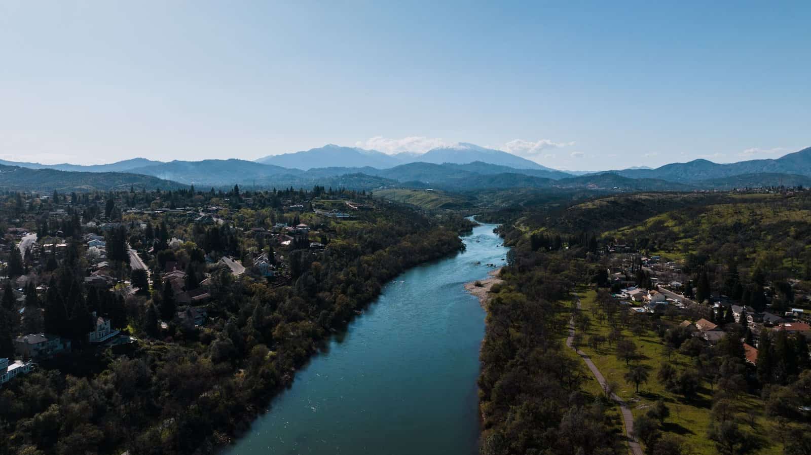A stunning aerial view of Redding, CA, featuring the Sacramento River and distant mountains.