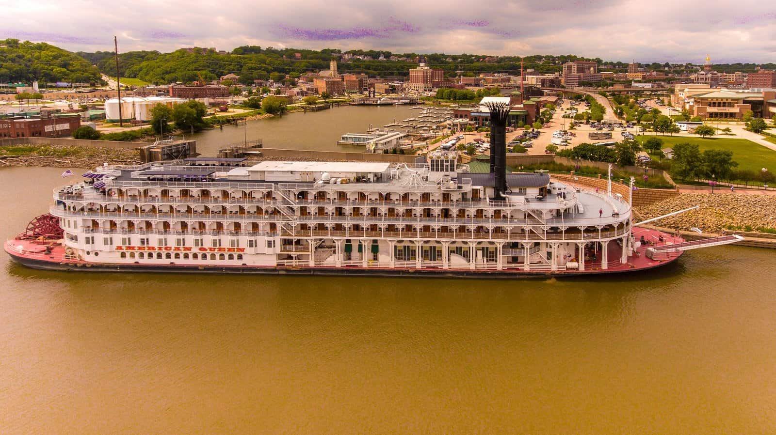 Aerial shot of the American Queen steamboat moored at Dubuque harbor, capturing the scenic view of the surroundings.