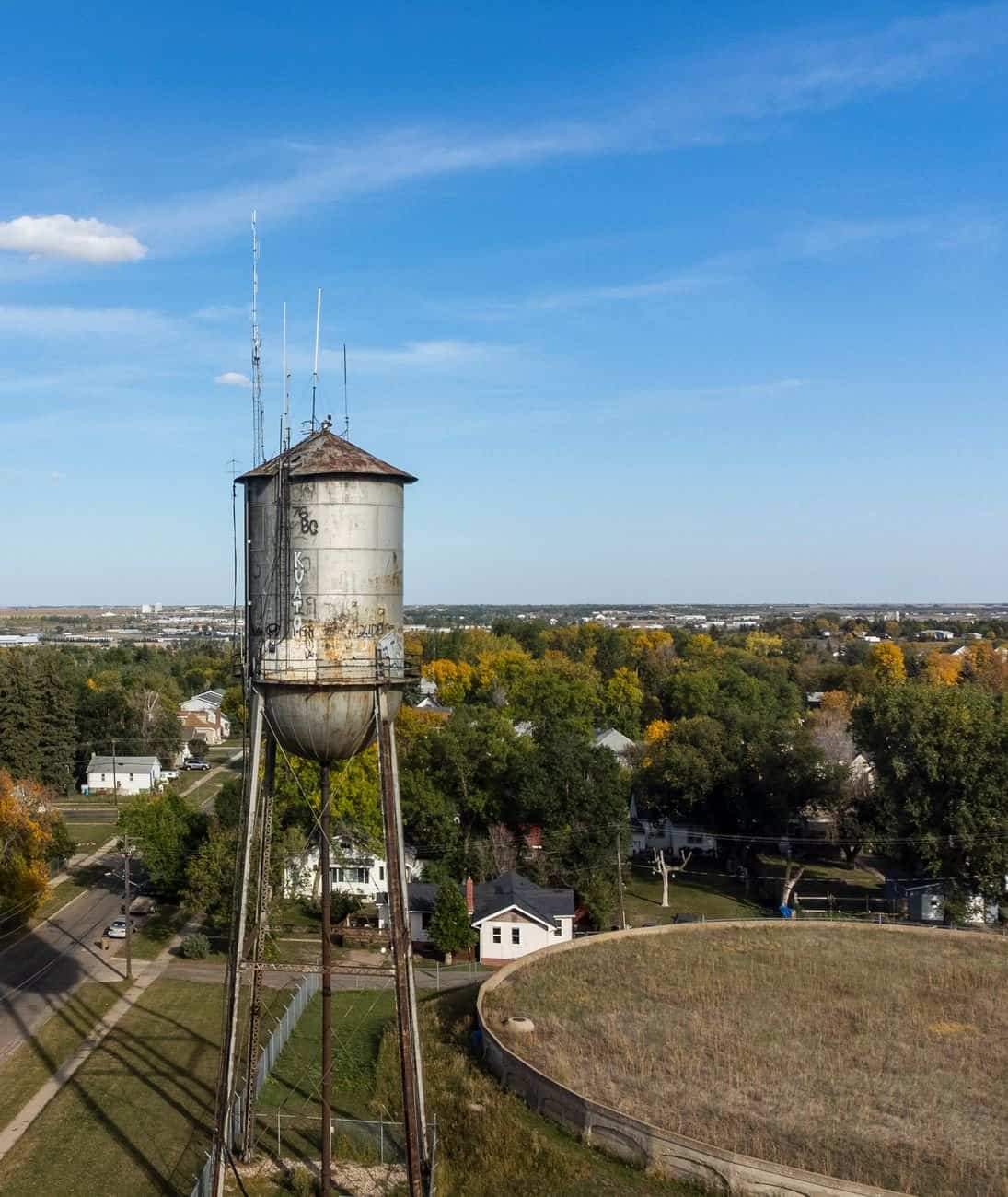 Aerial view of a historic water tower in Minot, ND under a clear blue sky.