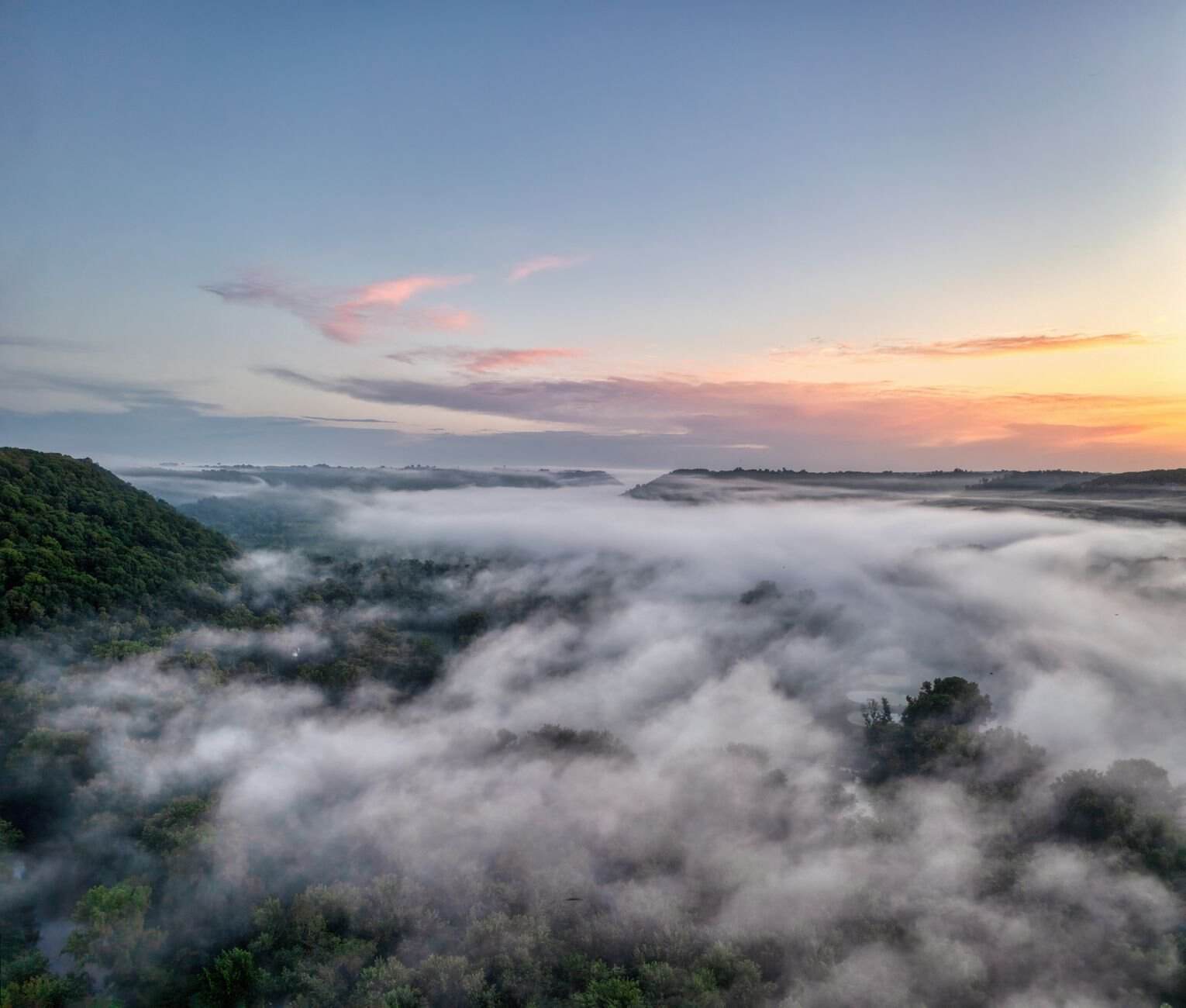 Breathtaking aerial view of a misty valley forest at sunrise in Maiden Rock, Wisconsin.