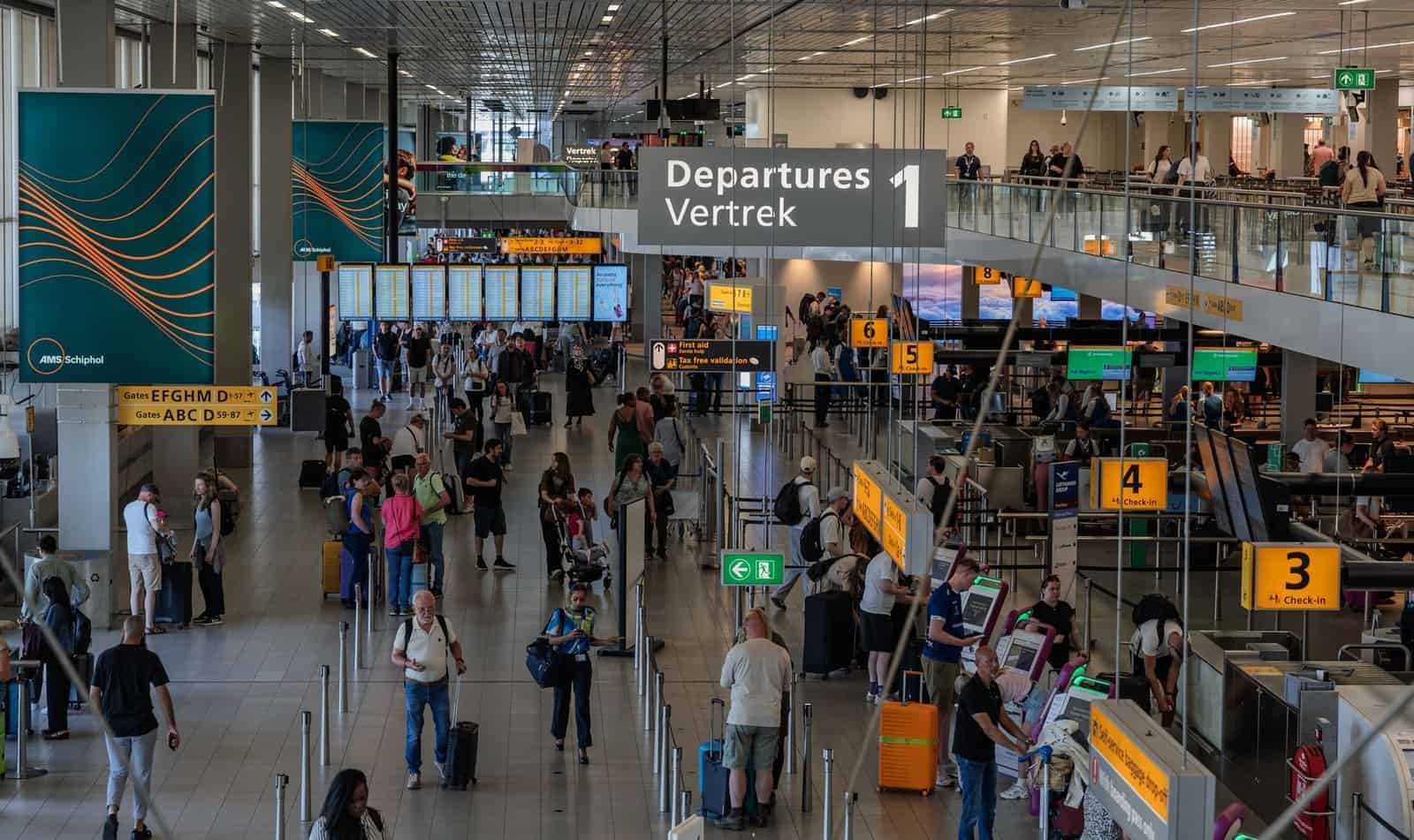 Crowds in the departure area of Amsterdam's Schiphol Airport, showcasing bustling travel activity.