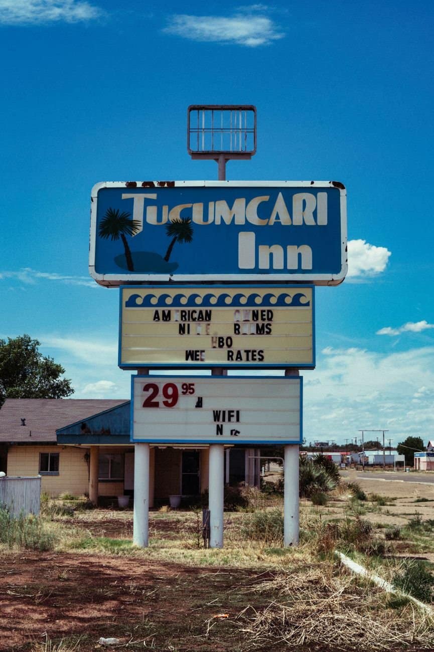 Retro motel sign for Tucumcari Inn with summer blue sky, evoking nostalgia and road trip vibes.