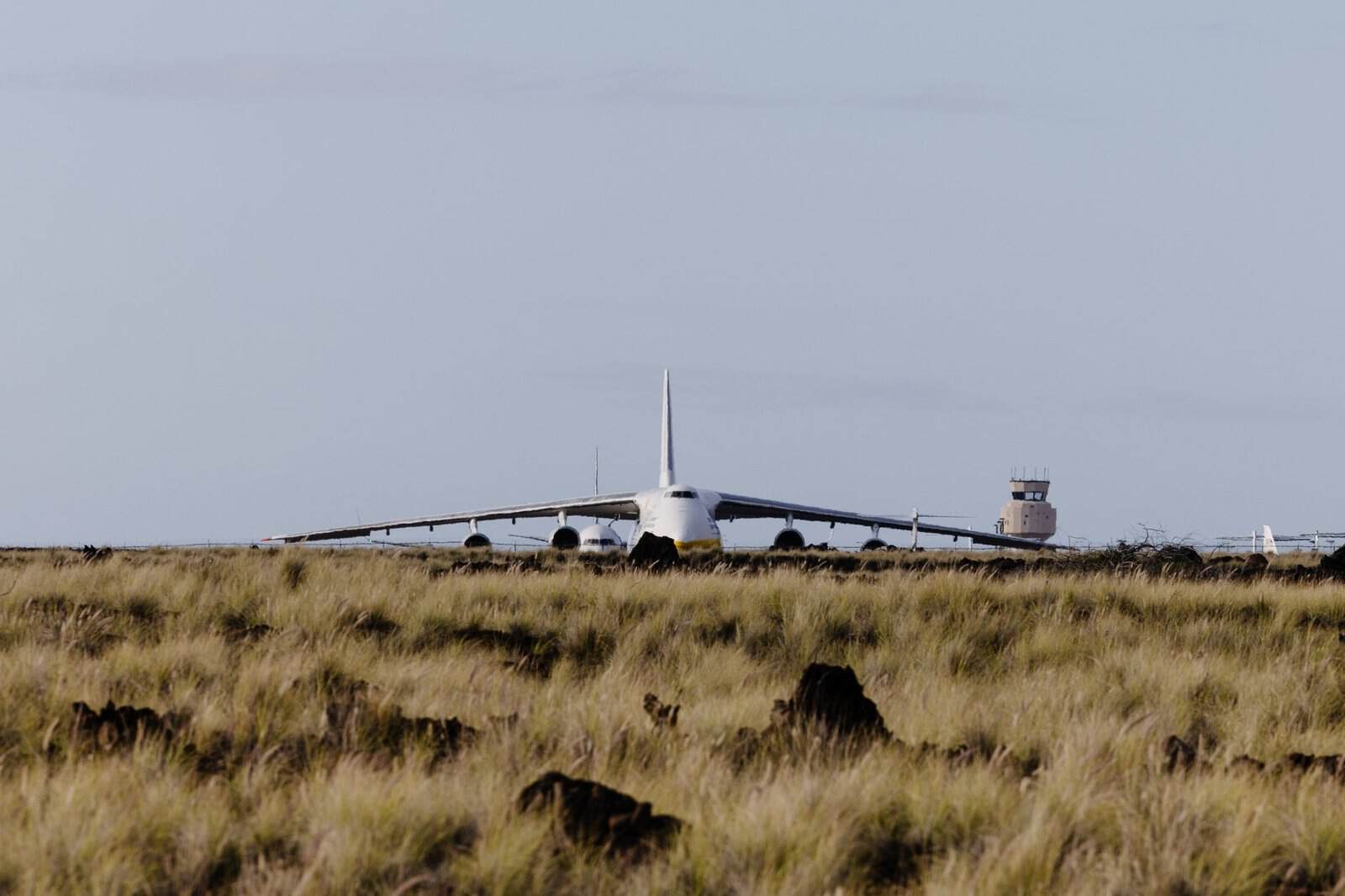 A large aircraft, possibly Antonov, on a runway surrounded by grasslands at Kailua-Kona Airport.