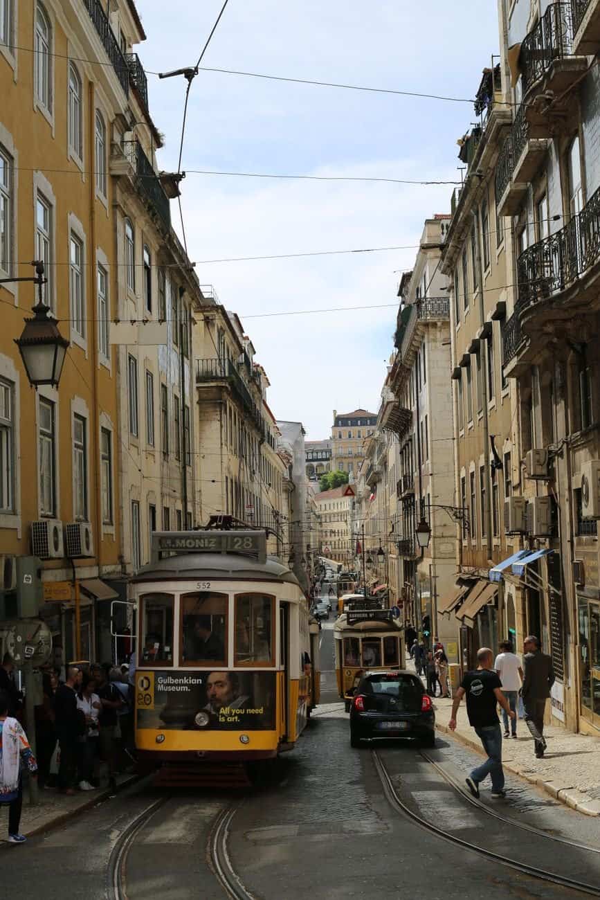 Classic Lisbon street with trams and townhouses, showcasing urban life and architecture.