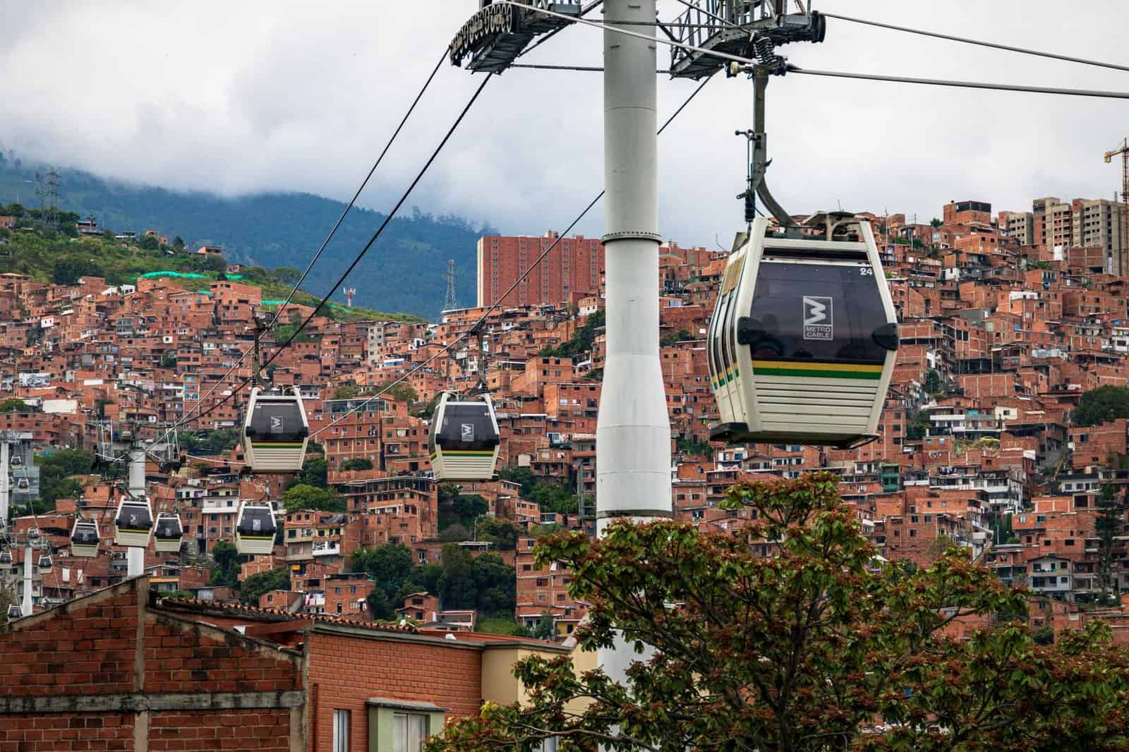Cable cars traversing the vibrant hillsides of Medellín, with terracotta buildings and lush greenery below.
