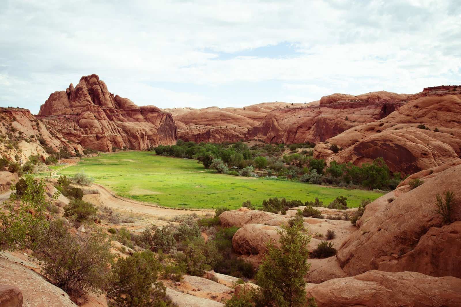 Explore the breathtaking red rock formations and lush valley in Utah's desert landscape.