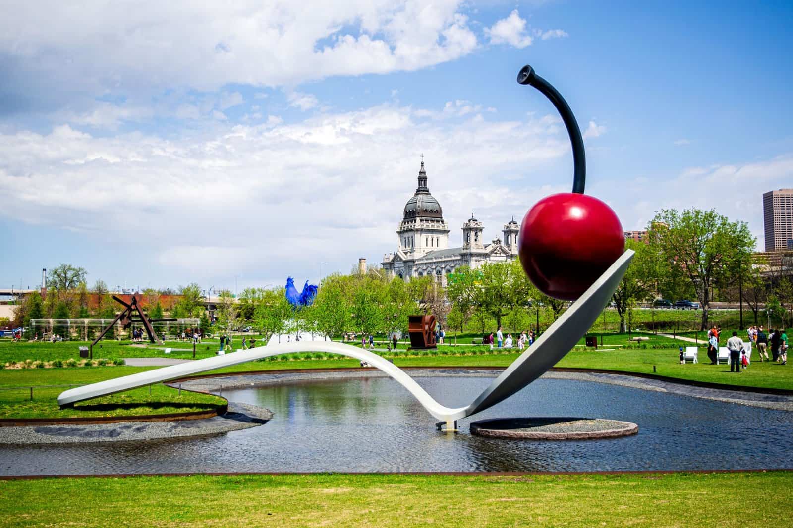 Famous Spoonbridge and Cherry sculpture in Minneapolis park with cityscape background.