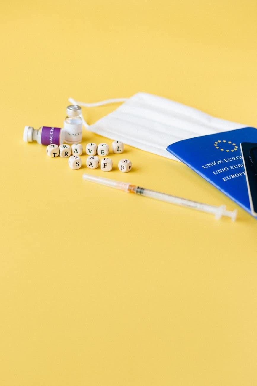 Essential travel safety items including mask, syringe, and passport for a pandemic-ready journey.