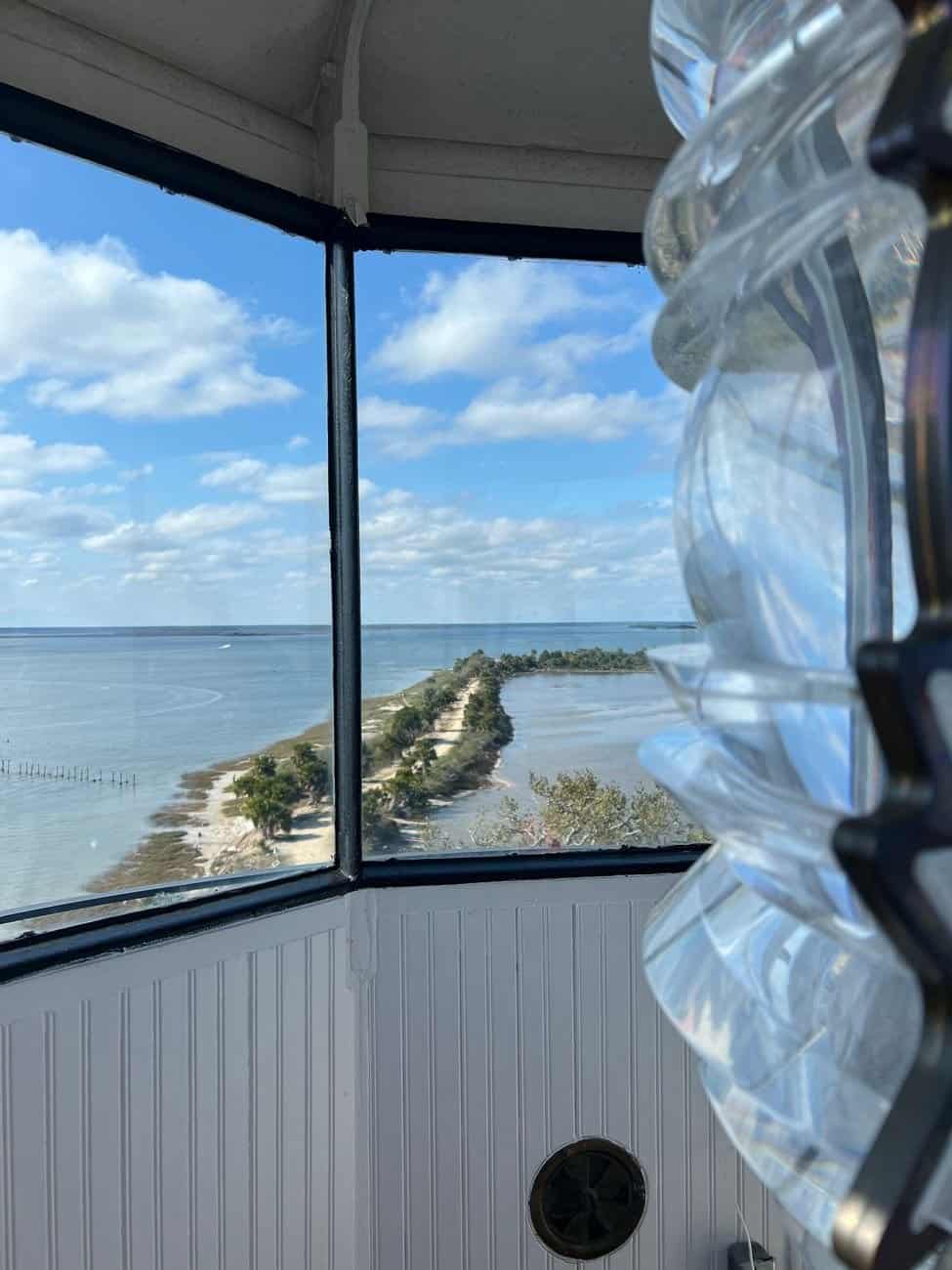 View from inside a lighthouse overlooking a coastline with clear blue skies.