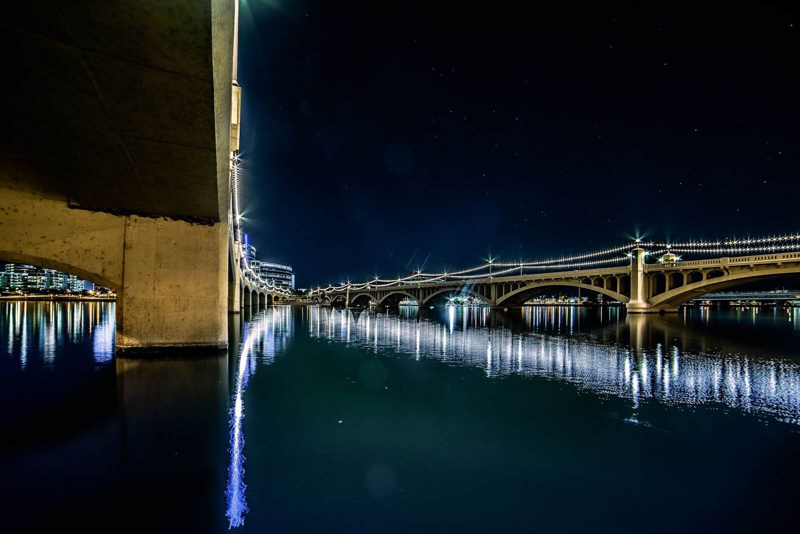 Stunning nighttime shot of Tempe Town Lake bridge with reflections, stars, and city lights.
