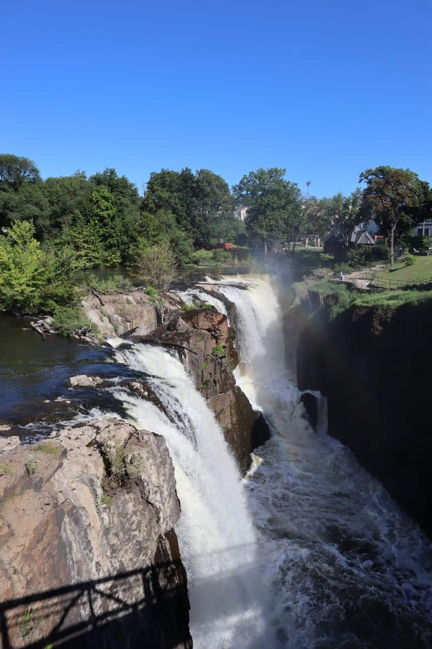 A stunning waterfall cascading amidst lush greenery under a clear blue sky.