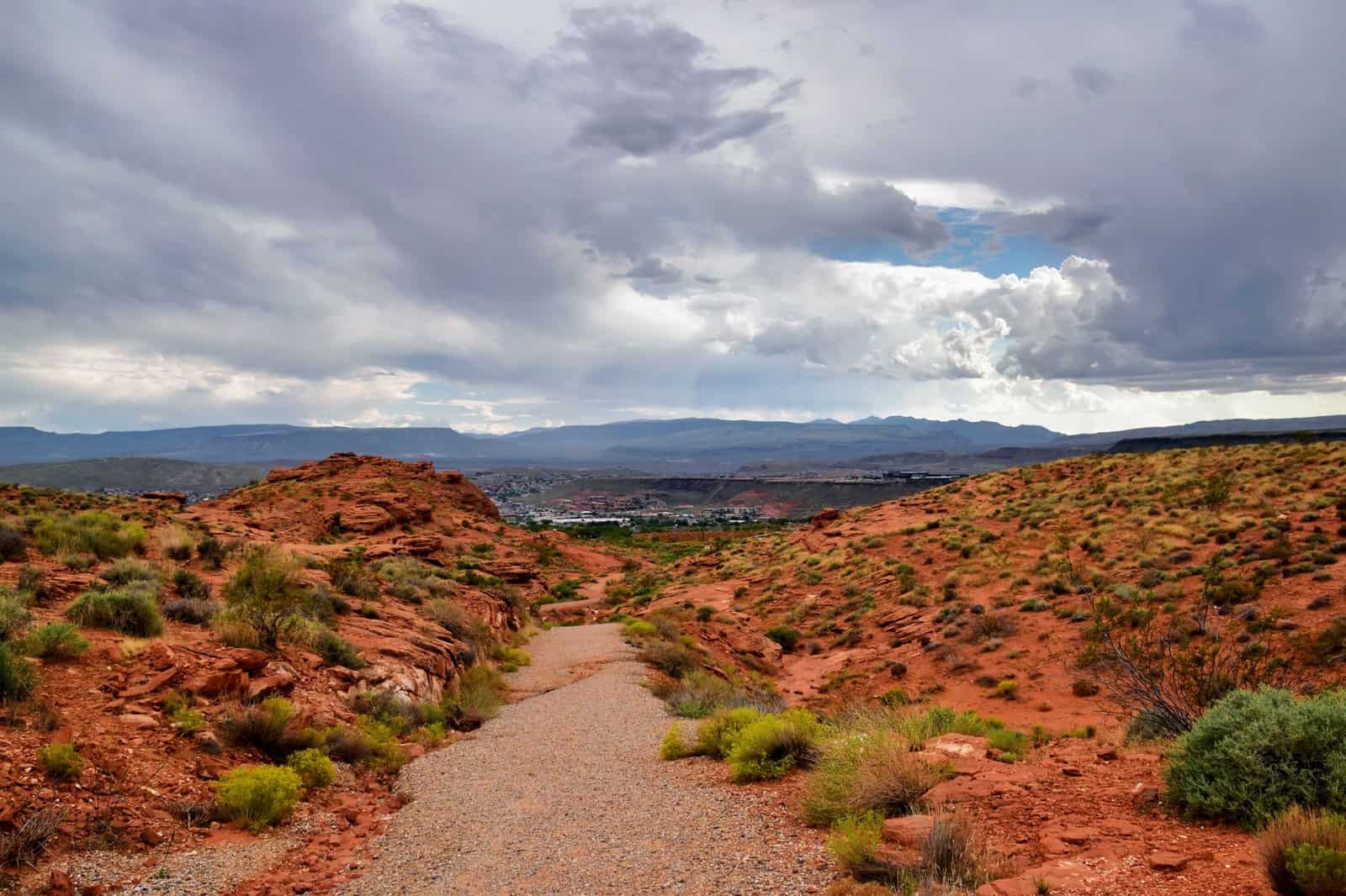 Peaceful desert path with stunning views of St. George, Utah under a dramatic sky.